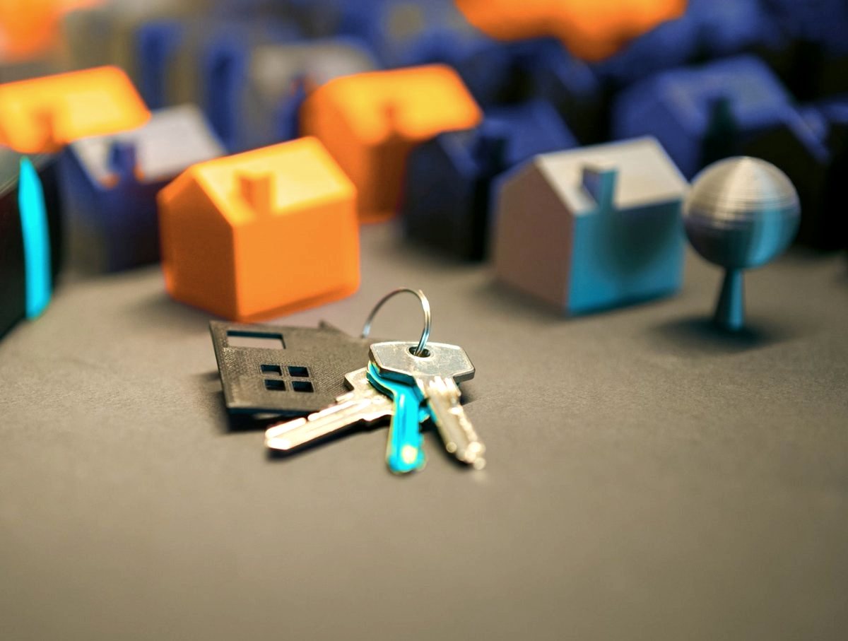 A set of house keys in front of small model houses in navy and orange